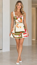 Front view of model wearing white floral scarf print corset mini dress with pom-pom trim
