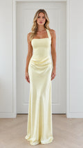 Full front view of model wearing pale yellow halter neck satin maxi evening gown