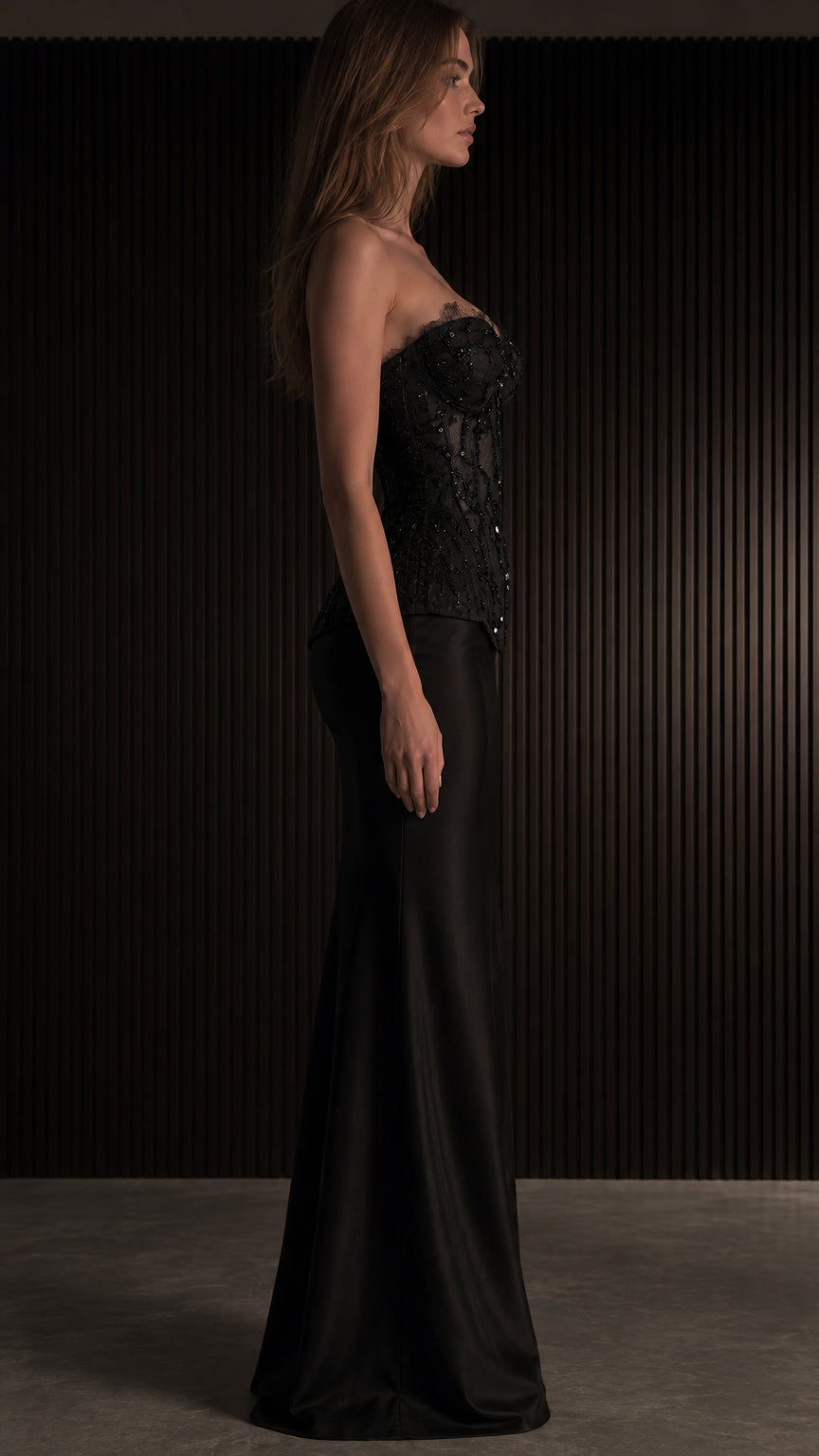 Side profile of woman wearing black corset bustier and matching black satin maxi skirt