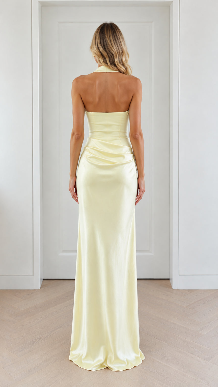 Back view of model wearing pale yellow open back satin maxi dress