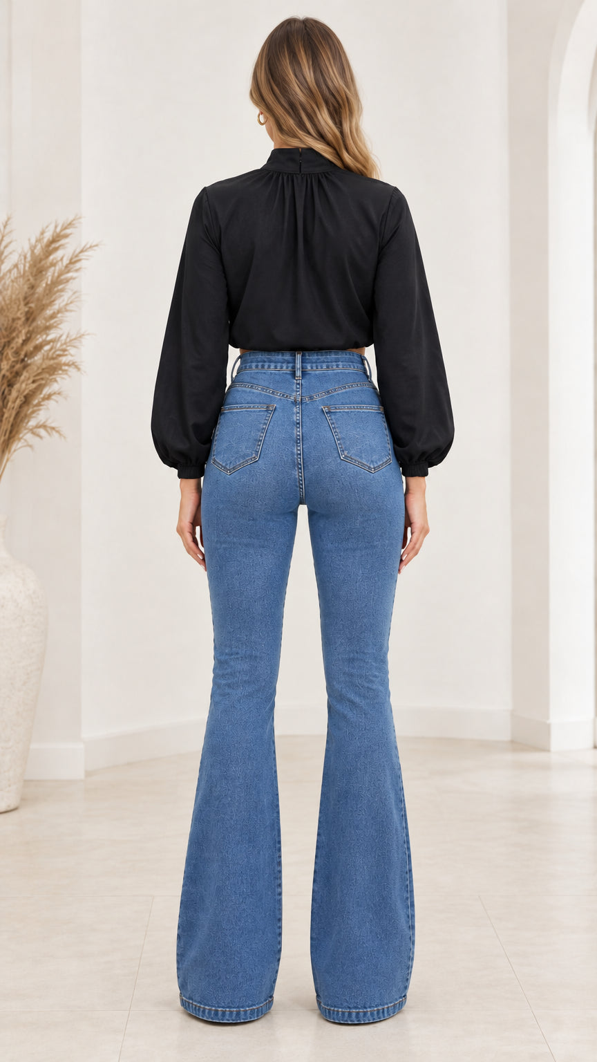 Back view of model wearing black crop top and blue flare jeans with back pockets
