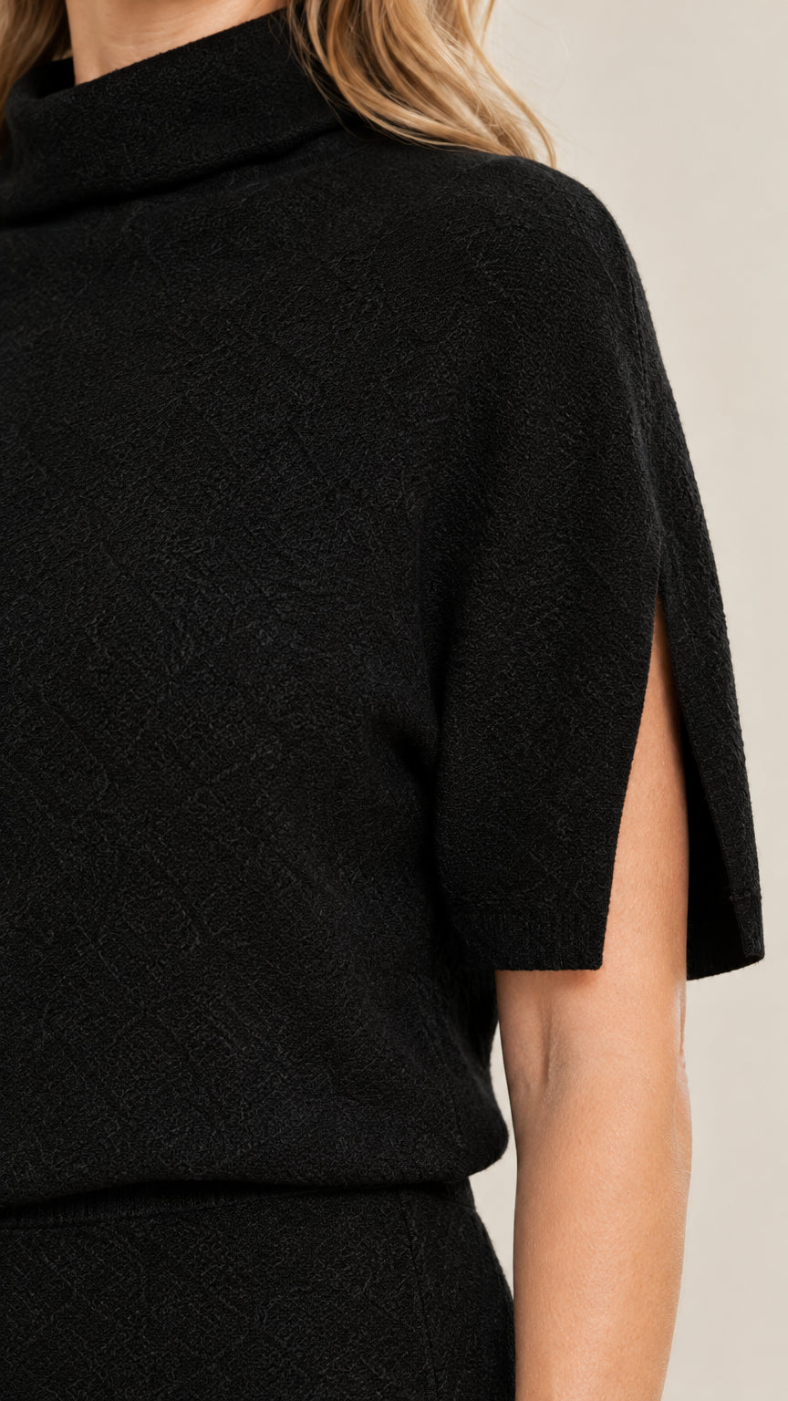 Close-up detail of black fine knit fabric and sleeve slit opening