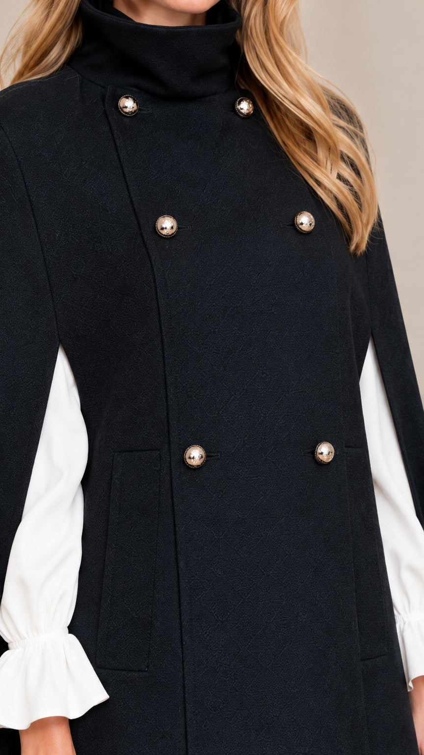 Close-up detail of metallic dome buttons, stand collar, and slit sleeve on black cape coat