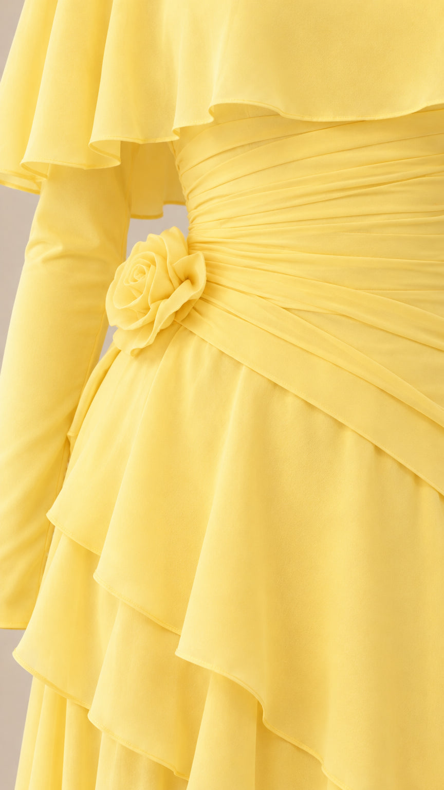 Close-up detail of the ruched bodice, floral rosette accent, and cascading skirt ruffles