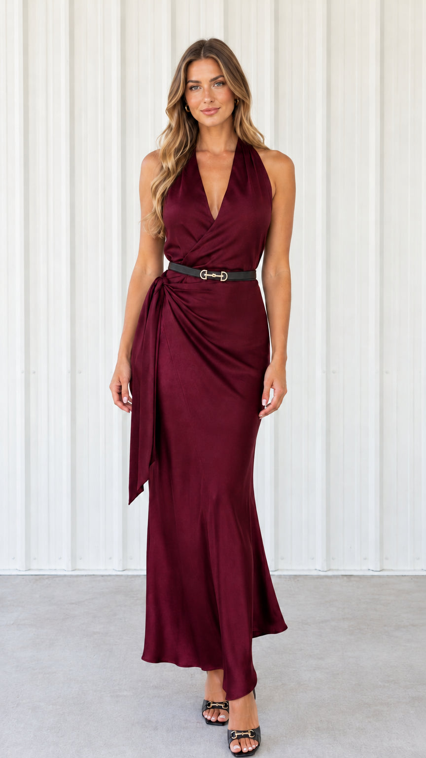 Full-length front view of woman wearing burgundy wine halter neck satin wrap maxi dress